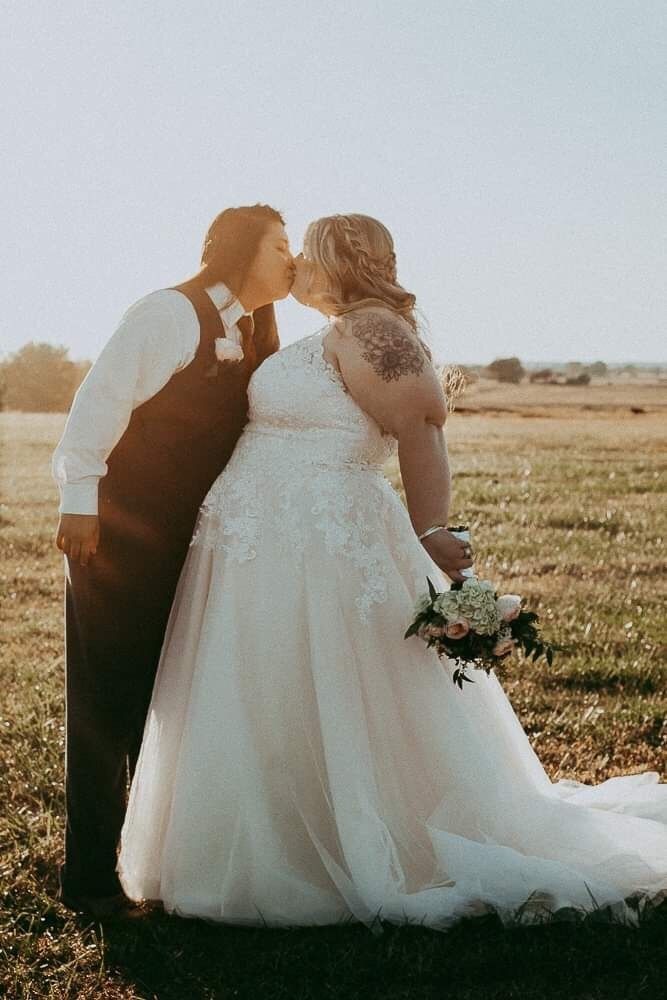 a bride and groom kissing in the middle of an open field on their wedding day