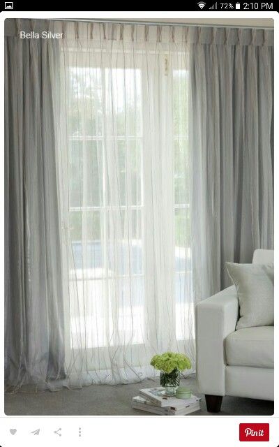 a white couch sitting in front of a window next to a table with flowers on it