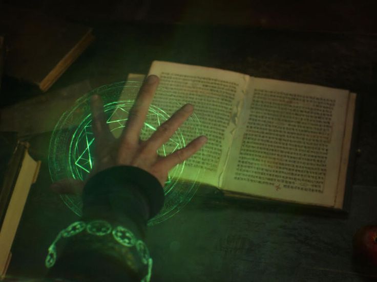 a person's hand on top of an open book next to a green light