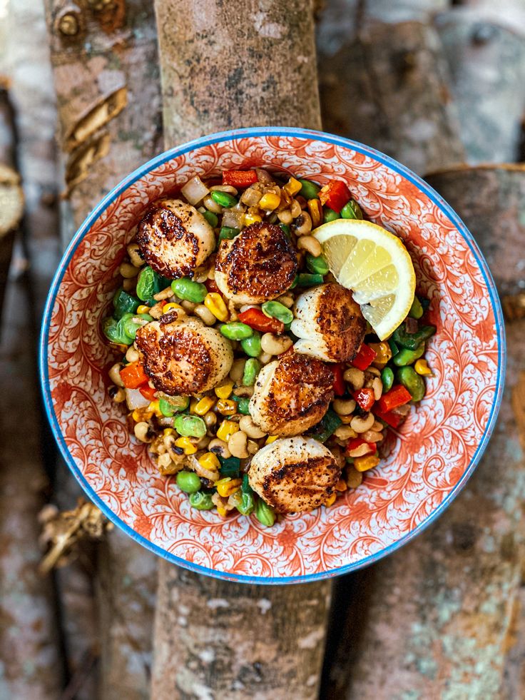 a bowl filled with meat and vegetables on top of a tree trunk in the woods