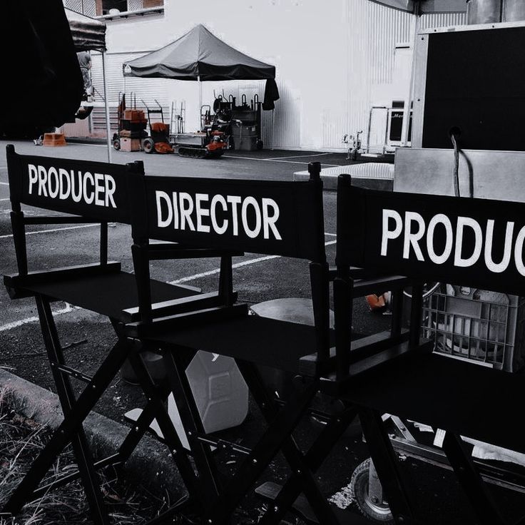 two director chairs sitting next to each other in front of a movie set on the street