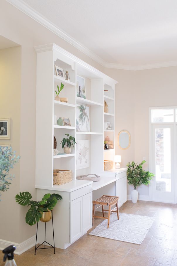 a living room filled with white furniture and lots of greenery on top of it