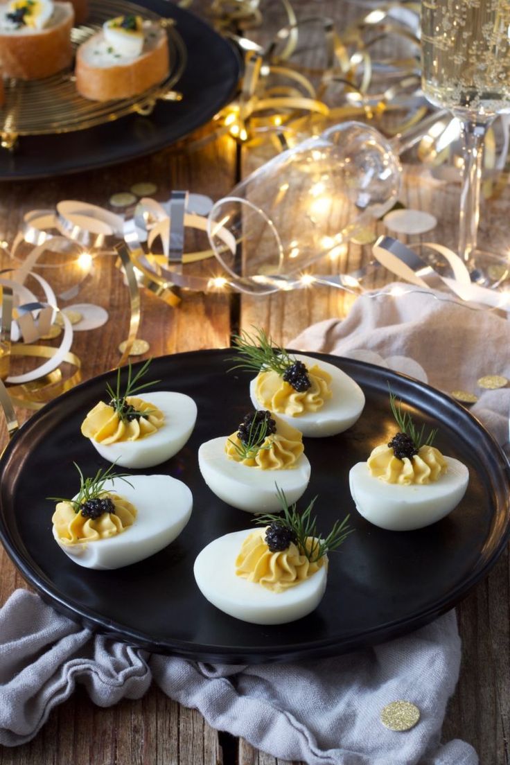 deviled eggs on a black plate with rosemary garnish and sprigs