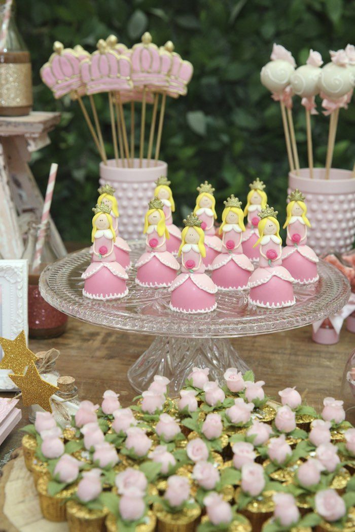 a table topped with lots of cupcakes covered in pink and yellow frosting