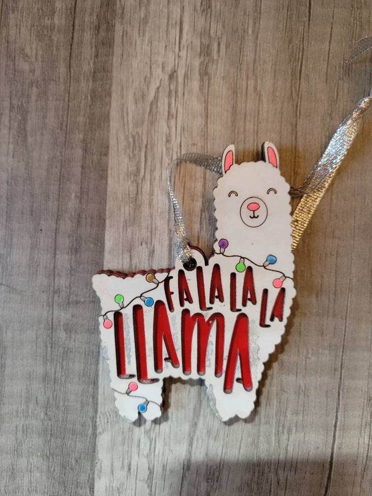 a llama shaped ornament hanging on a wooden surface with lights around it