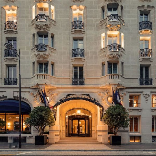 the hotel is lit up at night in front of an ornate building with balconies