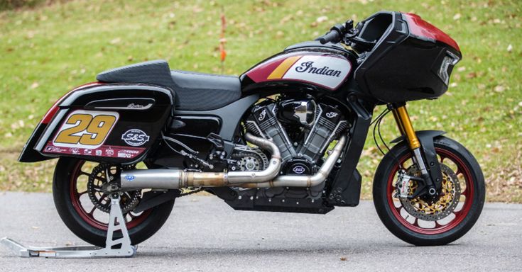 a red and black motorcycle parked on the side of a road next to some grass