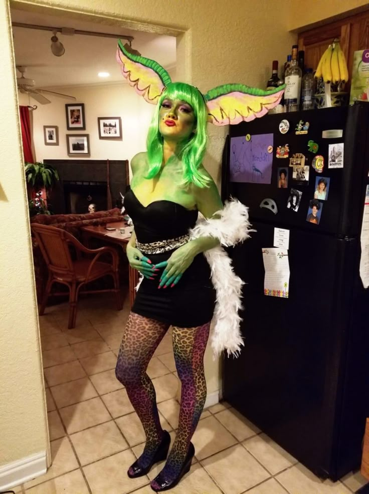 a woman with green hair and costume posing in front of a refrigerator