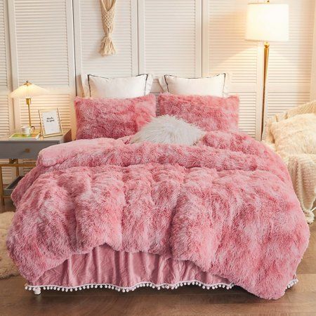 a bed covered in pink fur with pom poms