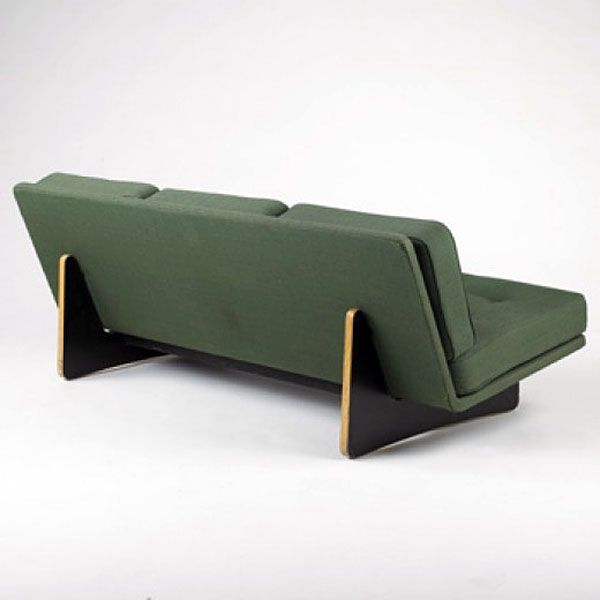 a green and black couch sitting on top of a white floor next to a wall