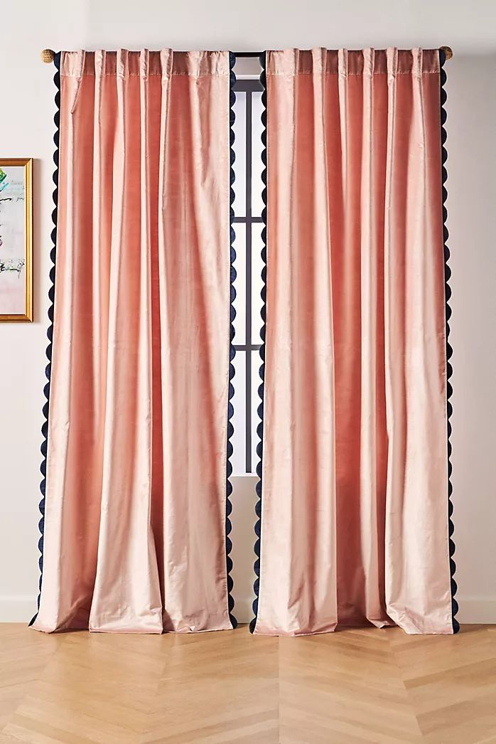 two pink curtains with black and white trims in front of a wooden flooring area