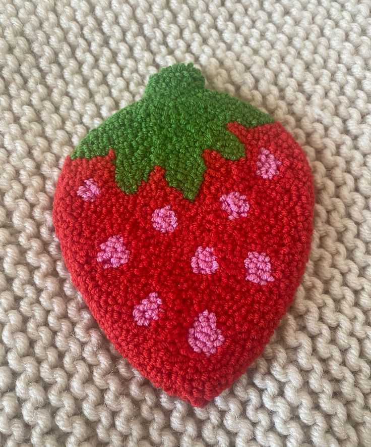 a crocheted strawberry on a white surface