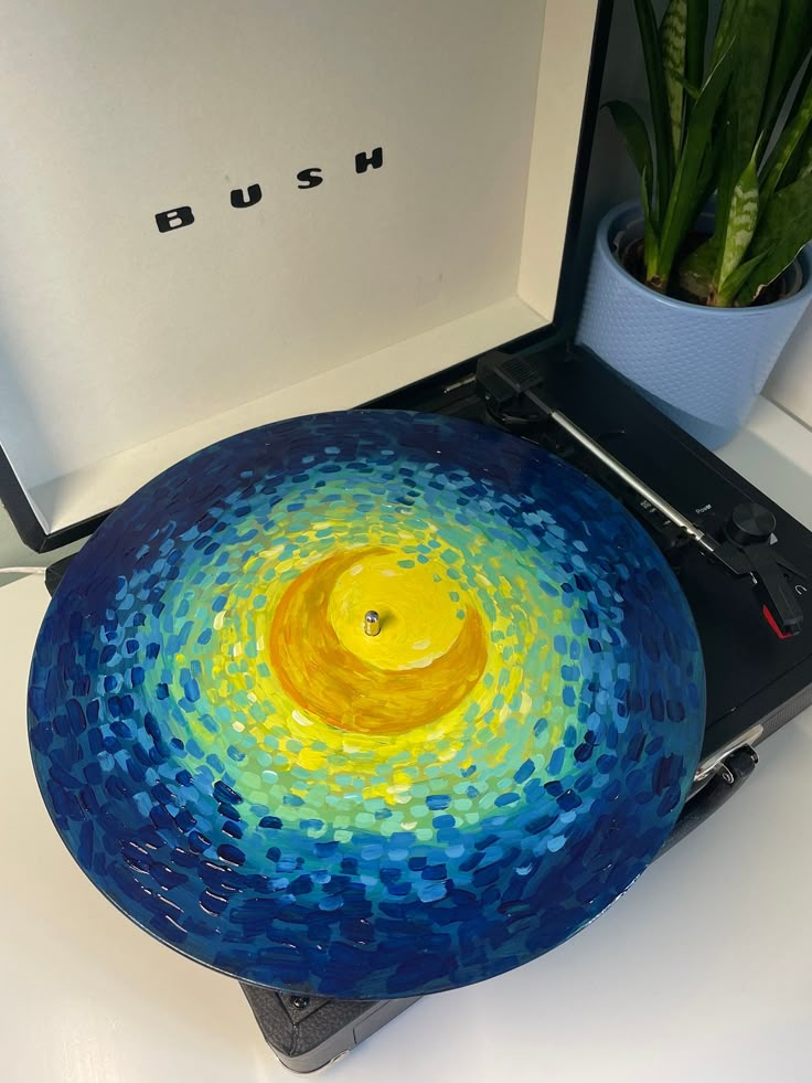 a blue and yellow plate sitting on top of a table next to a potted plant