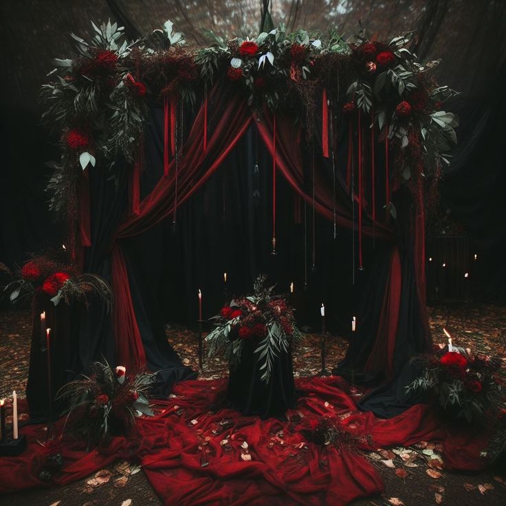 a red and black wedding set up with candles, flowers and greenery on the floor