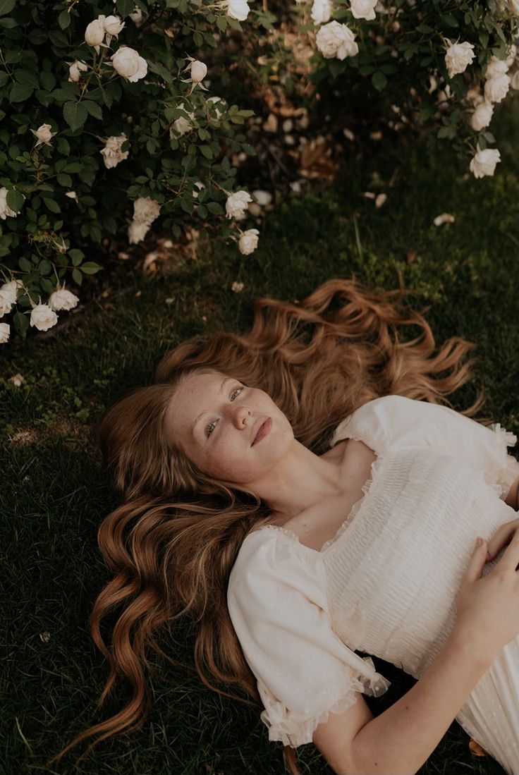 a woman laying on the ground with her hair blowing in the wind and eyes closed