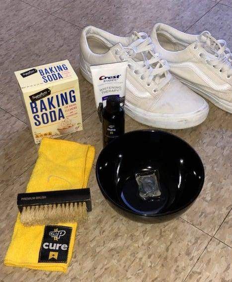 a pair of white tennis shoes sitting on top of a floor next to cleaning supplies