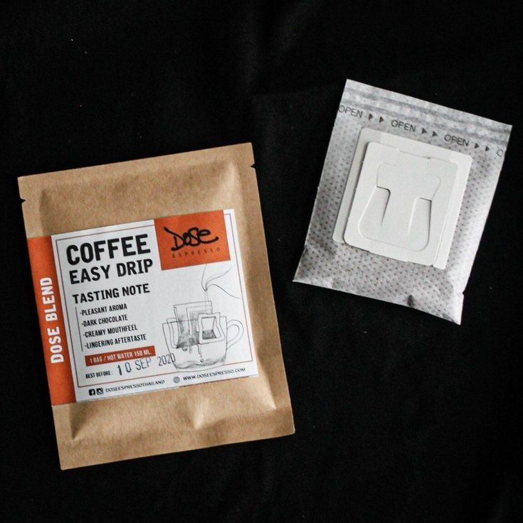 two packets of coffee sitting next to each other on a black tablecloth covered surface