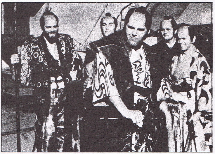 an old black and white photo of four men dressed in native garb standing next to each other