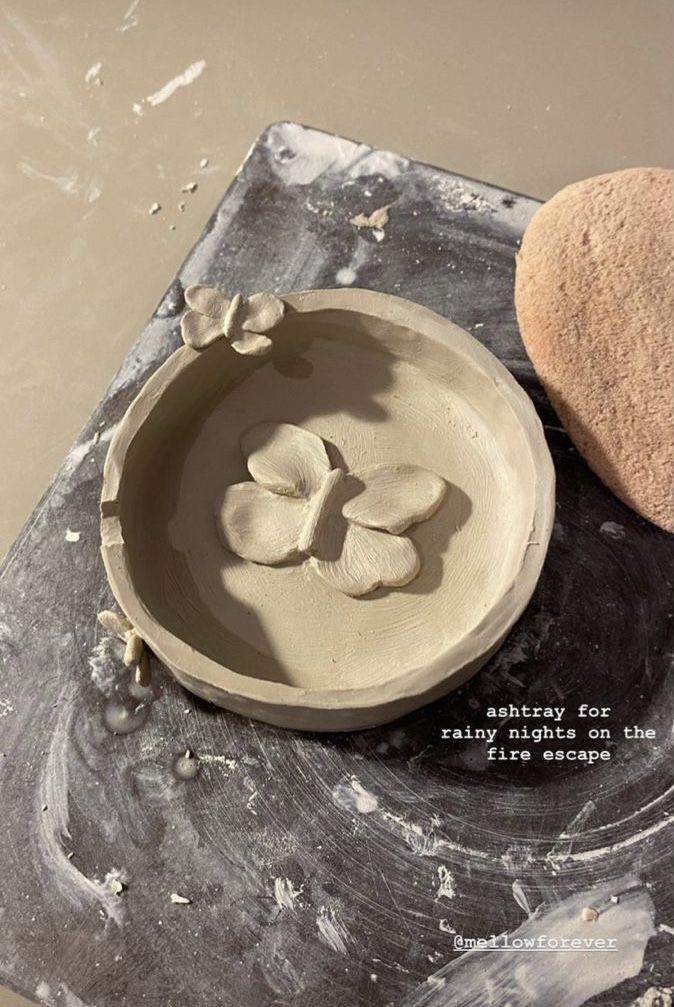 a clay bowl sitting on top of a table next to a heart shaped rock in the sand