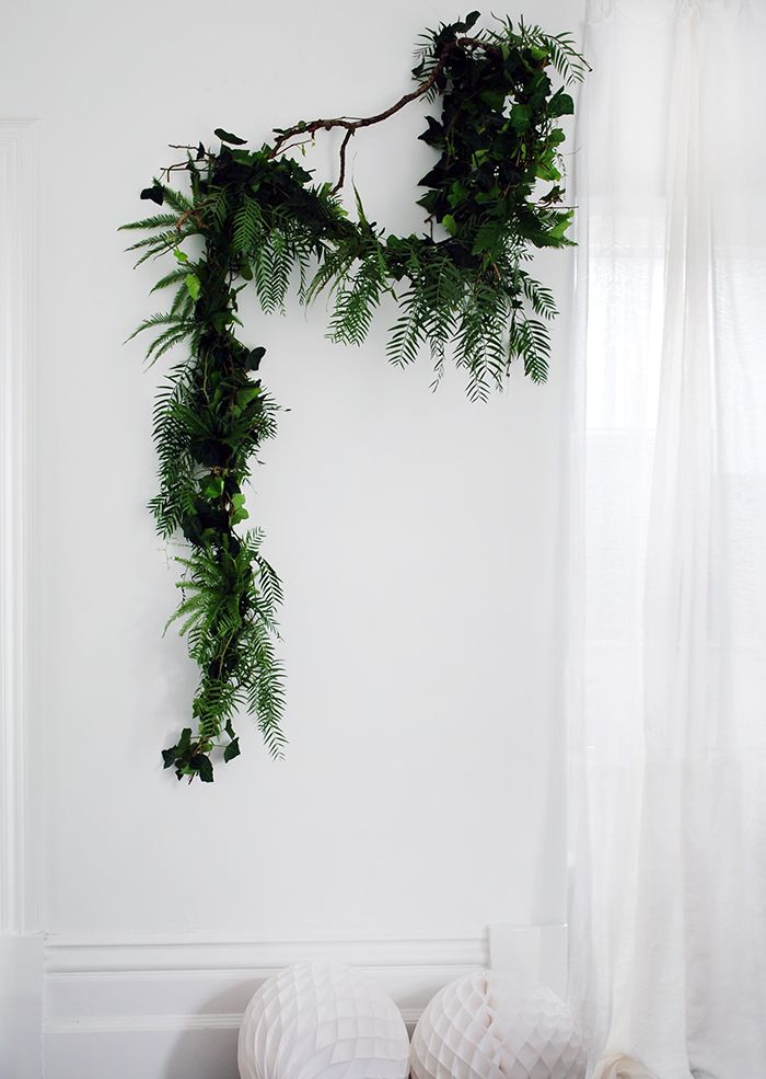 two white balls sitting on top of a wooden table next to a plant hanging from the wall