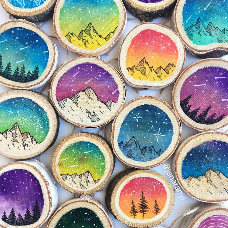 painted wooden slices with trees and mountains on them are arranged in the shape of magnets