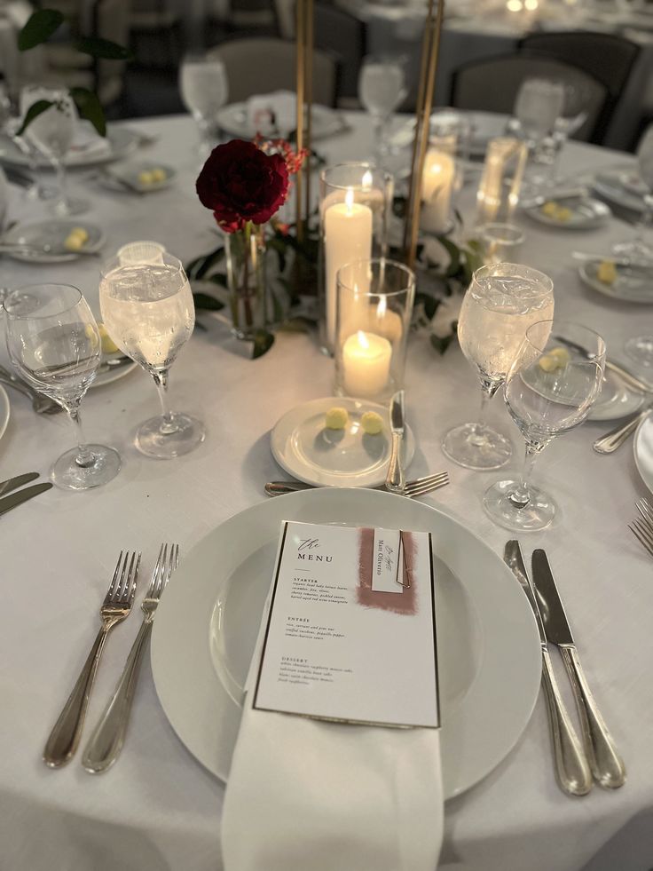 the table is set with silverware, candles and place settings for an elegant dinner