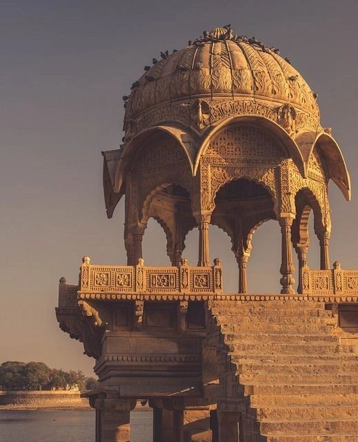 an ornate gazebo sits on the edge of a body of water with steps leading up to it