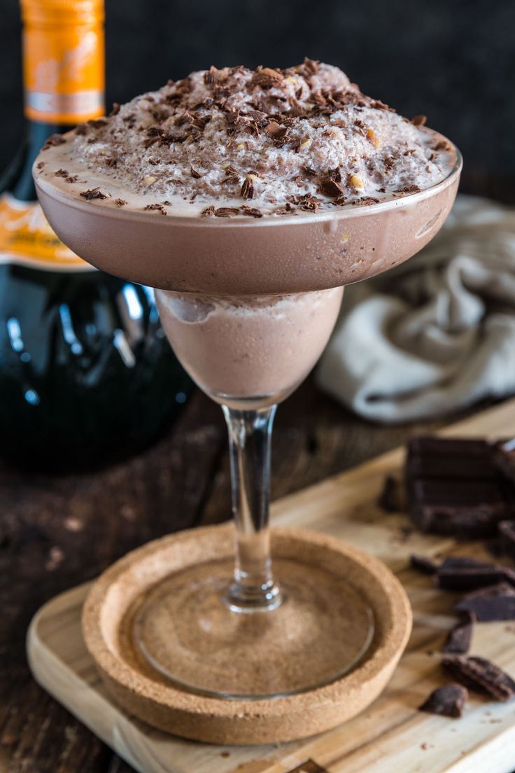 a chocolate dessert in a glass on a cutting board next to a bottle of booze