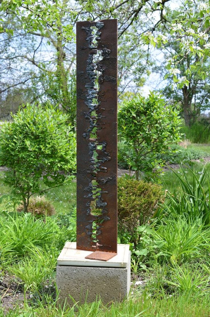 a tall metal sculpture sitting in the middle of a field