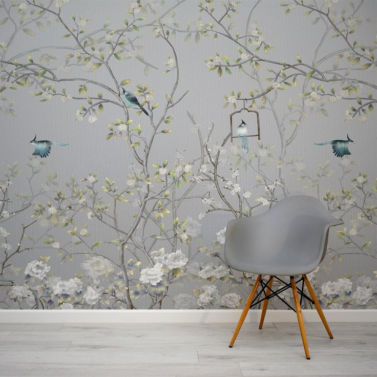 a chair sitting in front of a wallpapered with birds and flowers on it