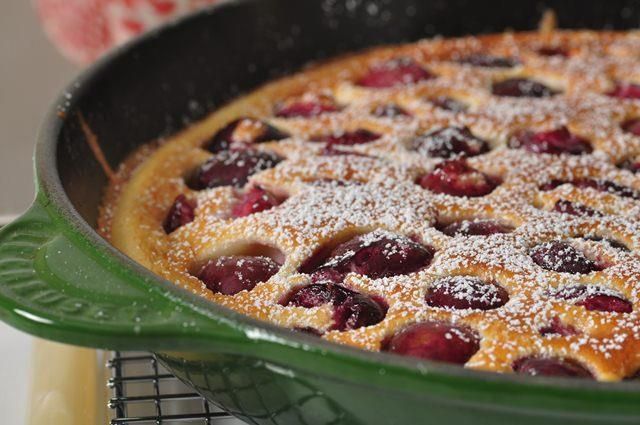 a cake in a pan with powdered sugar and cherries on the top is ready to be eaten