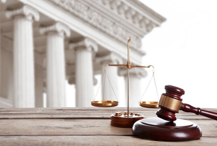 a judge's hammer and scale sitting on top of a wooden table in front of a building