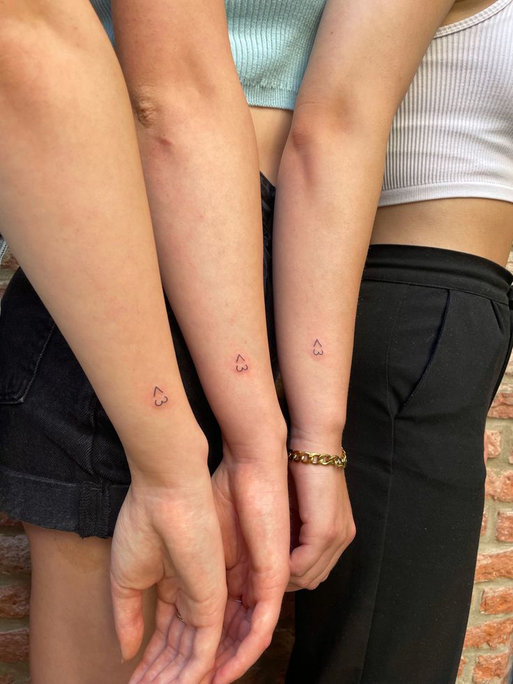 two people holding hands with small tattoos on their arms