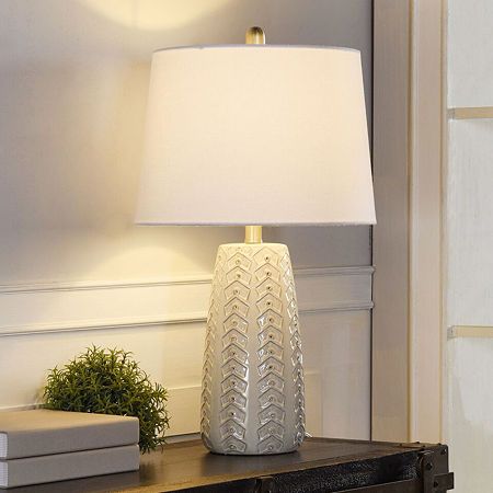 a white lamp sitting on top of a wooden table next to a book and plant