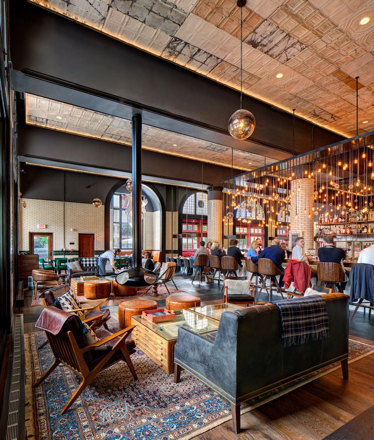 people are sitting at tables in a large room with high ceilings and wood flooring