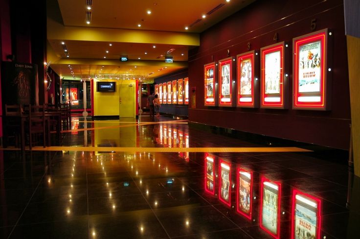 an empty lobby with red and yellow lights on the walls, and black tile flooring