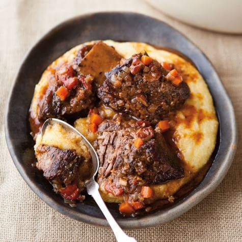 a bowl filled with meat and potatoes on top of a table