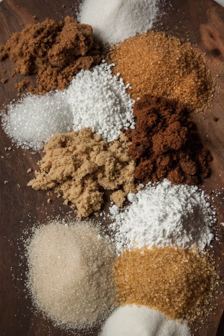 several different types of spices on a wooden board with white and brown powder in the middle