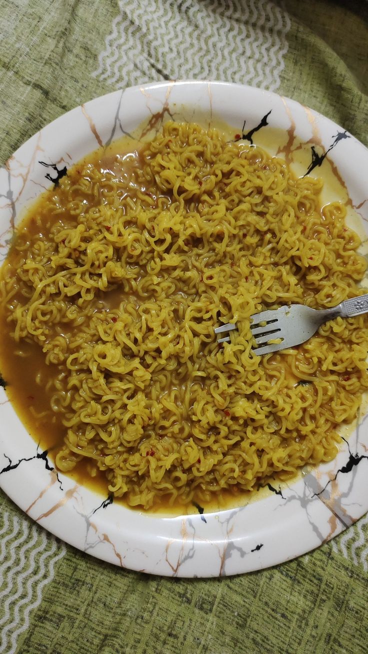 a white plate topped with noodles and gravy on top of a green table cloth