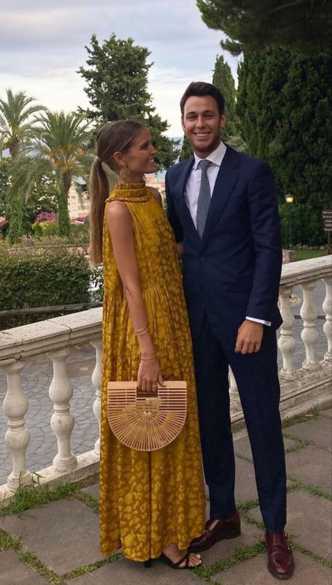 a man in a suit and tie standing next to a woman wearing a yellow dress