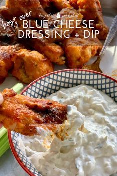 blue cheese dressing and dip with celery sticks in the foreground, chicken wings in the background