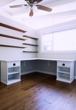 an empty room with some shelves and a ceiling fan in the corner on top of it