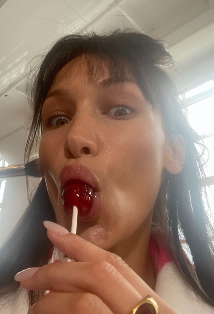 a woman with long black hair is holding a toothbrush in her mouth and sticking it into the air