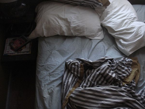 an unmade bed with pillows and blankets on it