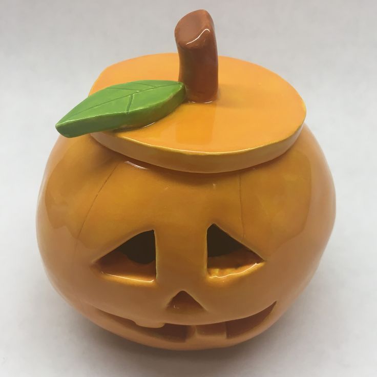 an orange pumpkin shaped container with a green leaf sticking out of it's top