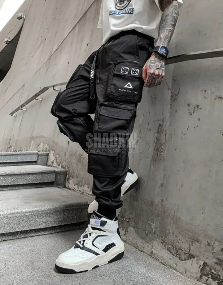 Design: Cyberpunk Technical pants: This techwear pants is the perfect garment to complete your Techwear outfit. Breathable materials: This techwear hoodie made of polyester, cotton and spandex can be worn all year round. Machine washable: 30 °C (86 °F) Cyberpunk techwear pants Crafted for the modern nomad, the Cyberpunk Pants echo the ethos of a dystopian world where fashion meets functionality. The pants are made from high-quality, durable materials that withstand the rigors of urban life. Their tactical design is accentuated with multiple cargo pockets, providing ample storage for all your gadgets and essentials. Whether you're navigating the chaotic streets of a bustling metropolis or embarking on an urban adventure, these pants ensure you're prepared for whatever comes your way. These