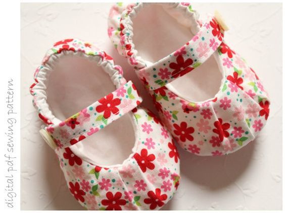 two baby shoes with flowers on them sitting next to each other in front of a white background