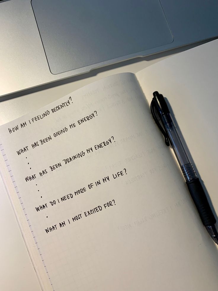 an open notebook sitting on top of a desk next to a pen