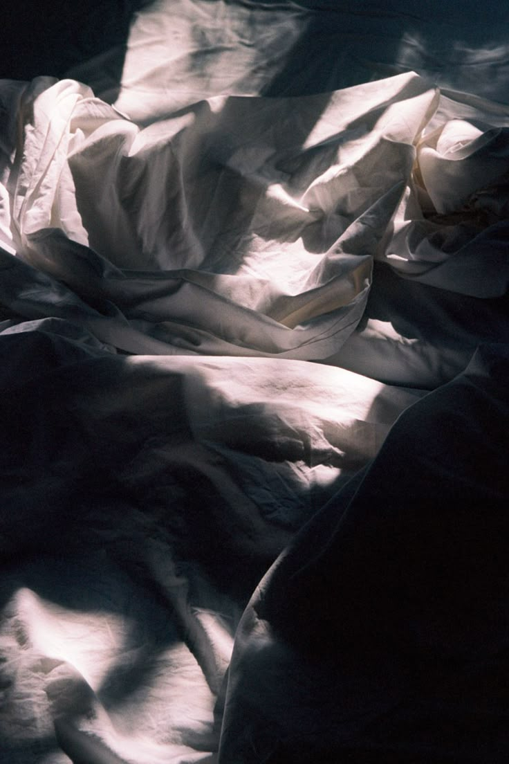 an unmade bed with white sheets and blankets on it's sides in the sunlight