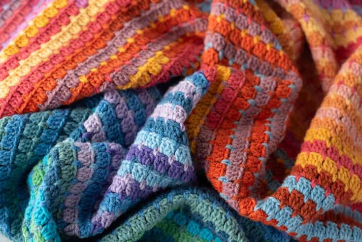 multicolored crocheted blanket laying on top of each other